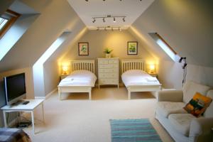 a attic room with two beds and a tv at Pirn Mill Self Catering Cottage in Cladich