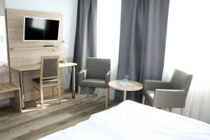 a hotel room with a bed and chairs and a television at Hotel Erlenstegen in Nürnberg