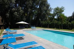 a swimming pool with blue lounge chairs and an umbrella at Hotel Villa Ciconia in Orvieto