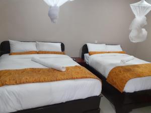 two beds with orange and white sheets in a room at Delight Lodge in Blantyre