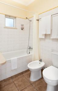 a white bathroom with a toilet and a tub and a sink at Hotel Rural Monte da Leziria in Santo André