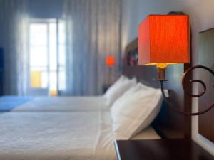 een slaapkamer met een bed met een lamp op een tafel bij Hotel Rural Monte da Leziria in Santo André