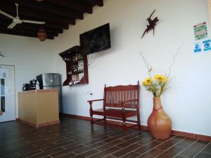 um quarto com um vaso de flores e uma cadeira em Gloria's Hotel em Playa Estacahuite
