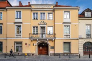 Ein gelbes Gebäude, an dem eine Frau vorbeigeht. in der Unterkunft P&O Serviced Apartments Old Town Podwale in Warschau