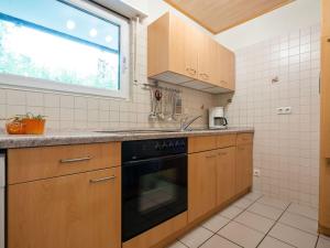 a kitchen with wooden cabinets and a black dishwasher at Holiday home in Kyllburg Eifel near the forest in Kyllburg