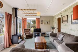 - un salon avec un canapé et une télévision dans l'établissement Cedar Cottage - Tauranga Taupo Holiday Home, à Kuratau
