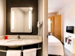 a bathroom with a sink and a mirror and a bed at ibis Uberaba in Uberaba
