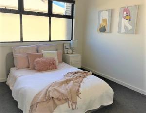 a bedroom with a white bed with pink pillows at Modern home in the heart of Mornington in Mornington