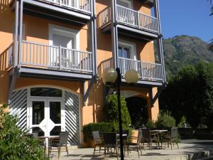 un bâtiment avec des chaises et des tables devant lui dans l'établissement Hôtel Chez Pierre d'Agos, à Agos-Vidalos