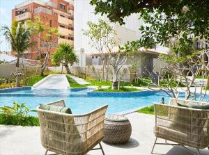 a swimming pool with two chairs in front of a building at HOTEL STRATA NAHA in Naha