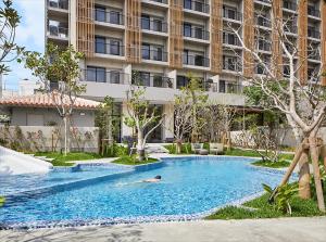 a man swimming in a swimming pool in front of a building at HOTEL STRATA NAHA in Naha