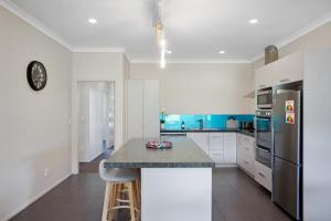 eine Küche mit weißen Schränken und einer Arbeitsplatte in der Unterkunft Sky Blue Retreat - Waihi Beach Holiday Home in Waihi Beach