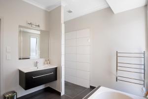 a white bathroom with a sink and a mirror at Sky Blue Retreat - Waihi Beach Holiday Home in Waihi Beach +17 photos