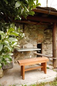 un banc en bois assis devant un bâtiment en pierre dans l'établissement Belcolle, il bello della tranquillità, à Chiavenna