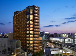 a tall building with lights on in a city at HOTEL STRATA NAHA in Naha