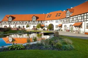 a building with an orange roof next to a pond at Penzion statek Bernard in Královské Poříčí