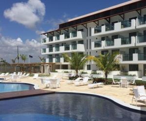 un hôtel avec une piscine en face d'un bâtiment dans l'établissement Laguna Beach Flat, à Porto de Galinhas