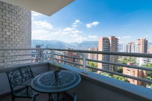 einen Balkon mit einem Tisch und Stühlen sowie Aussicht in der Unterkunft Apartamentos Poblado Alejandría by HOUSY HOST in Medellín