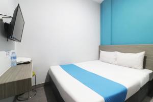 ein Hotelzimmer mit einem Bett und einem TV in der Unterkunft Sambina in Jakarta