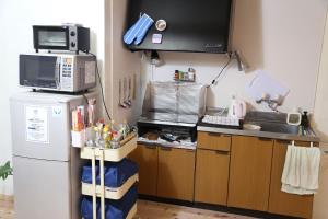 a small kitchen with a refrigerator and a microwave at PERCH GUEST HOUSE in Tatsuno