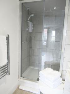 a shower in a bathroom with a stack of towels at Queen Street Apartments in Wolverhampton