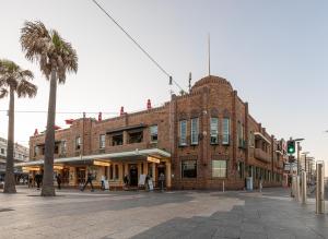 ein großes Backsteingebäude an einer Stadtstraße mit einer Palme in der Unterkunft Stay at Hotel Steyne in Sydney