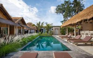 a pool at a villa with chairs and a resort at Nusa Majesty in Nusa Penida