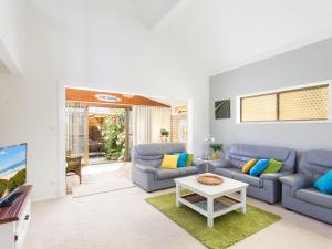 uma sala de estar com sofás azuis e uma mesa em Waterside at Point Road em Tuncurry