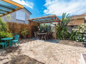 eine Terrasse mit einer hölzernen Pergola sowie einem Tisch und Stühlen in der Unterkunft Waterside at Point Road in Tuncurry