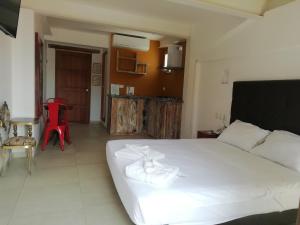 a bedroom with a white bed and a red chair at Casa Ebano 967 in Cartagena de Indias