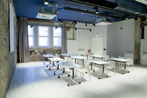 una clase con mesas y sillas en una habitación en Catalonia Berlin Mitte en Berlín