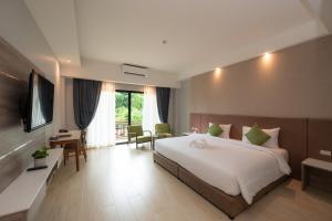 a hotel room with a large bed and a television at Phumontra Resort Nakhon Nayok in Nakhon Nayok