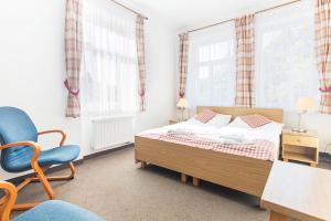 a bedroom with a bed and a chair and windows at Hotel Seifert in Nové Hamry