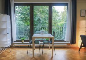 une table et des chaises dans une chambre avec une grande fenêtre dans l'établissement Park City Center Apartment, à Luxembourg