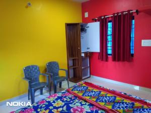 a bedroom with yellow and red walls and chairs at Shiva Shanti Guest House in Arambol