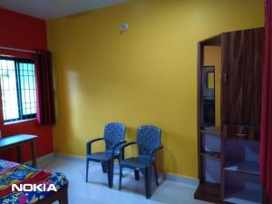 two blue chairs in a room with a yellow wall at Shiva Shanti Guest House in Arambol