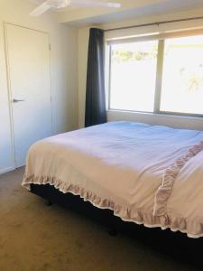 a bedroom with a bed and a large window at Mangawhai Room in Mangawhai