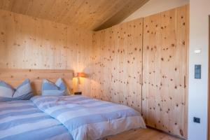 a bedroom with a bed with a wooden wall at Landhaus Silene in Sarnonico