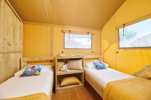 2 camas en una habitación pequeña con paredes amarillas en Camping Park Umag Glamping en Umag