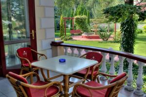 uma mesa e cadeiras numa varanda com vista para um jardim em Garni Hotel Vila Milord Resort em Palić