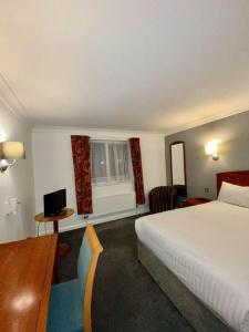 ein Hotelzimmer mit einem Bett, einem Schreibtisch und einem Fenster in der Unterkunft Roman Way Hotel in Cannock