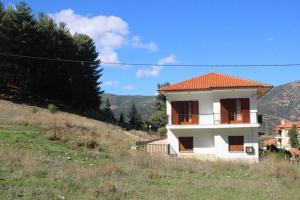 a white house with a red roof on a hill at Velia Guesthouse in Kalavrita