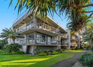 a large white building with palm trees in front of it at Wintersview 8 - Lennox Head in Lennox Head