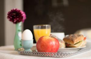 a tray with an apple and an egg and a glass of orange juice at Topperyd Bed & Breakfast in Nässjö +28 photos