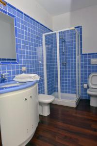 La salle de bains est pourvue de carrelage bleu, de toilettes et d'une douche. dans l'établissement Appartamento signorile con vista Caprera, à La Maddalena