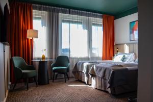トロンハイムにあるQuality Hotel Prinsenのベッド、テーブル、椅子が備わるホテルルームです。