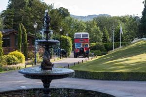 a double decker bus driving down a road with a fountain at Broadoaks Boutique Country House in Windermere