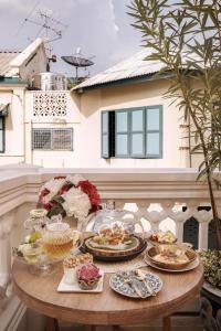 a table with plates of food on a balcony at The Knight House Bangkok in Bangkok