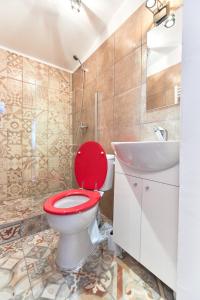 a bathroom with a red toilet and a sink at Stanford Apartments Gara de Nord in Bucharest