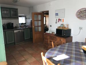 una cocina con mesa y una cocina con armarios verdes en El Olivo de Sansol, en Sansol